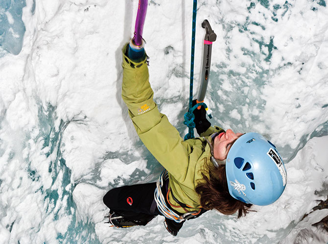Beck climbs an ice cliff. Her missing hand has a prosthetic attached to it.