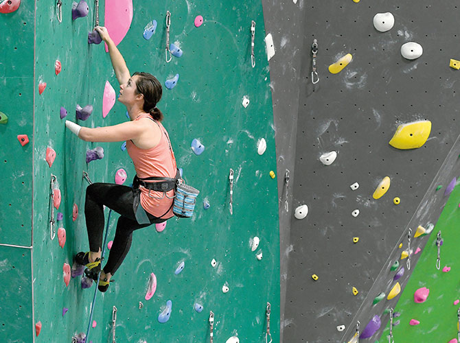 Beck climbs an indoor wall with only one hand.