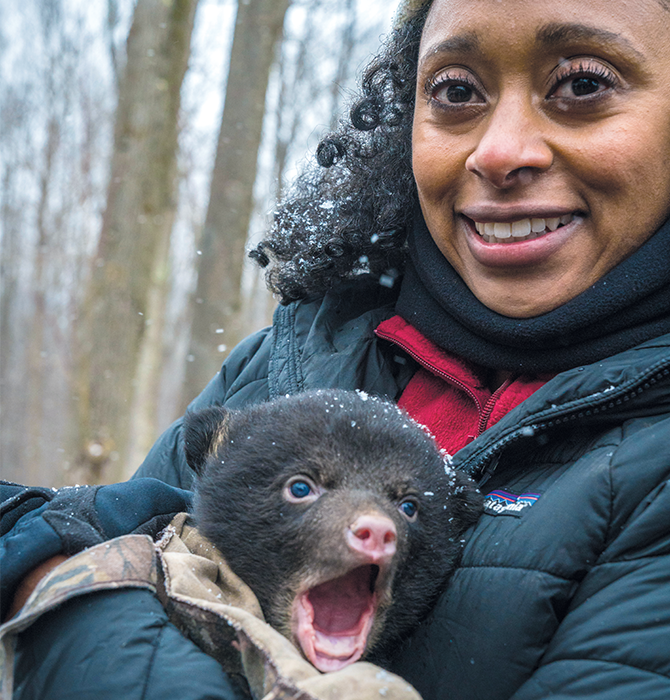 A woman smiling and holding a baby bear in her arms