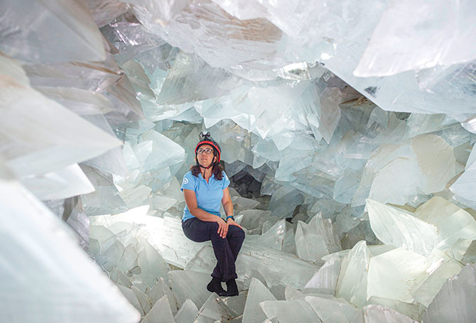 Woman sitting inside a cavern, surrounded by giant crystals